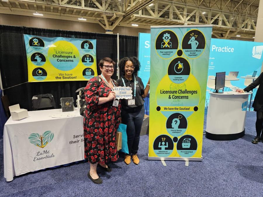 Two attendees holding an I Found the Solution sign at the LaMé Essentials booth